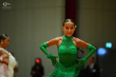 Dancesport competitor: Female dancer in center: bright green Latin dance dress with sequins, a halter n
