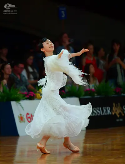 Dancesport competitor: Female dancer: long white ballroom dress featuring a voluminous lace and tulle s