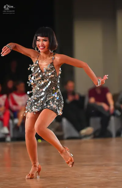 Dancesport competitor: Female dancer: short silver latin dress covered in large reflective sequins, wit