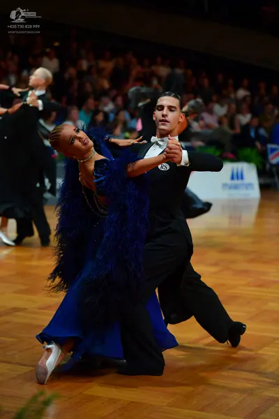 Dancesport competitor: Female dancer: deep blue ballgown featuring large blue feather or faux fur trim