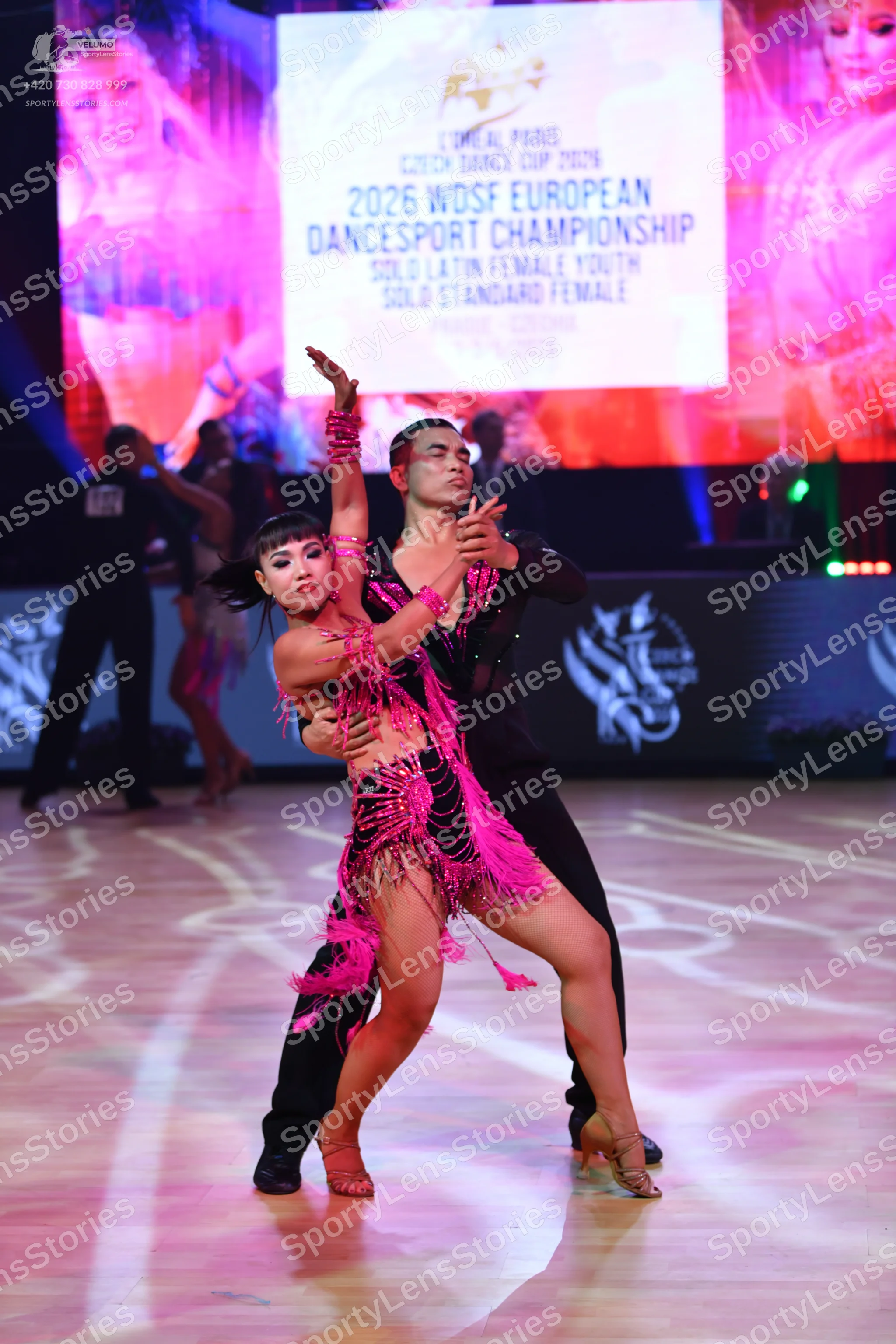 Dancesport competitor: Female dancer: pink Latin dance dress with long fringe and matching armbands