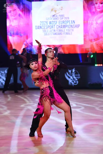Dancesport competitor: Female dancer: pink Latin dance dress with long fringe and matching armbands