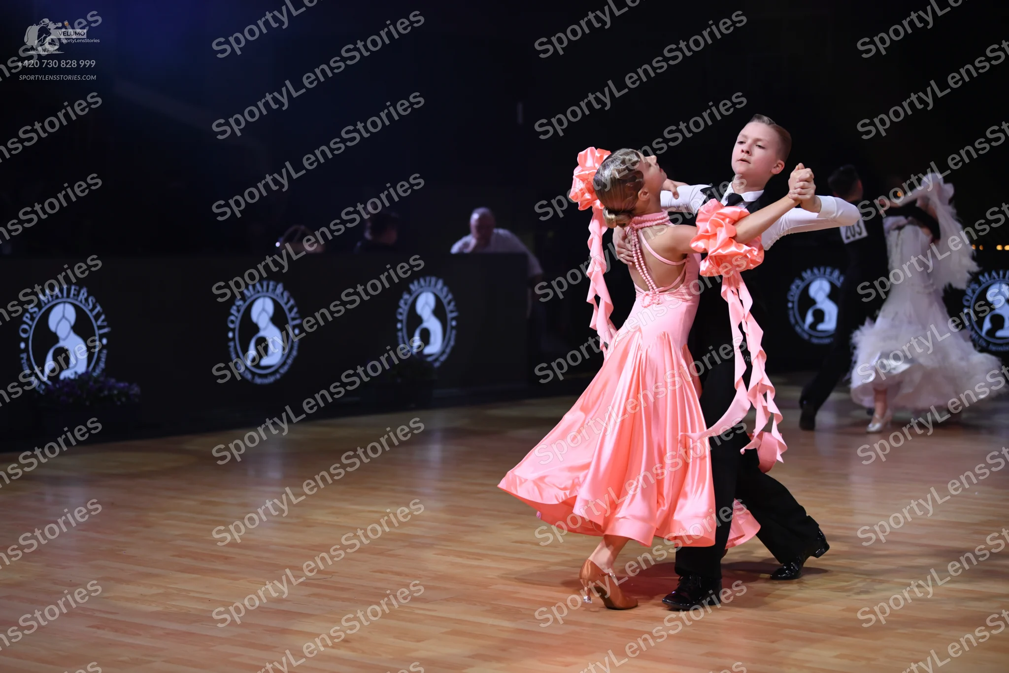 Dancesport competitor: Foreground female dancer: peach satin ballgown with a full, voluminous skirt and