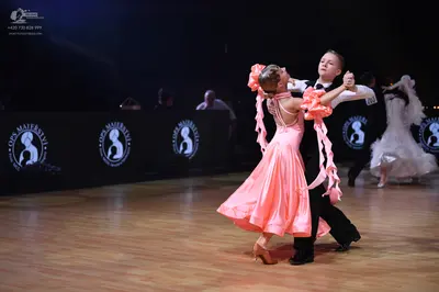 Dancesport competitor: Foreground female dancer: peach satin ballgown with a full, voluminous skirt and