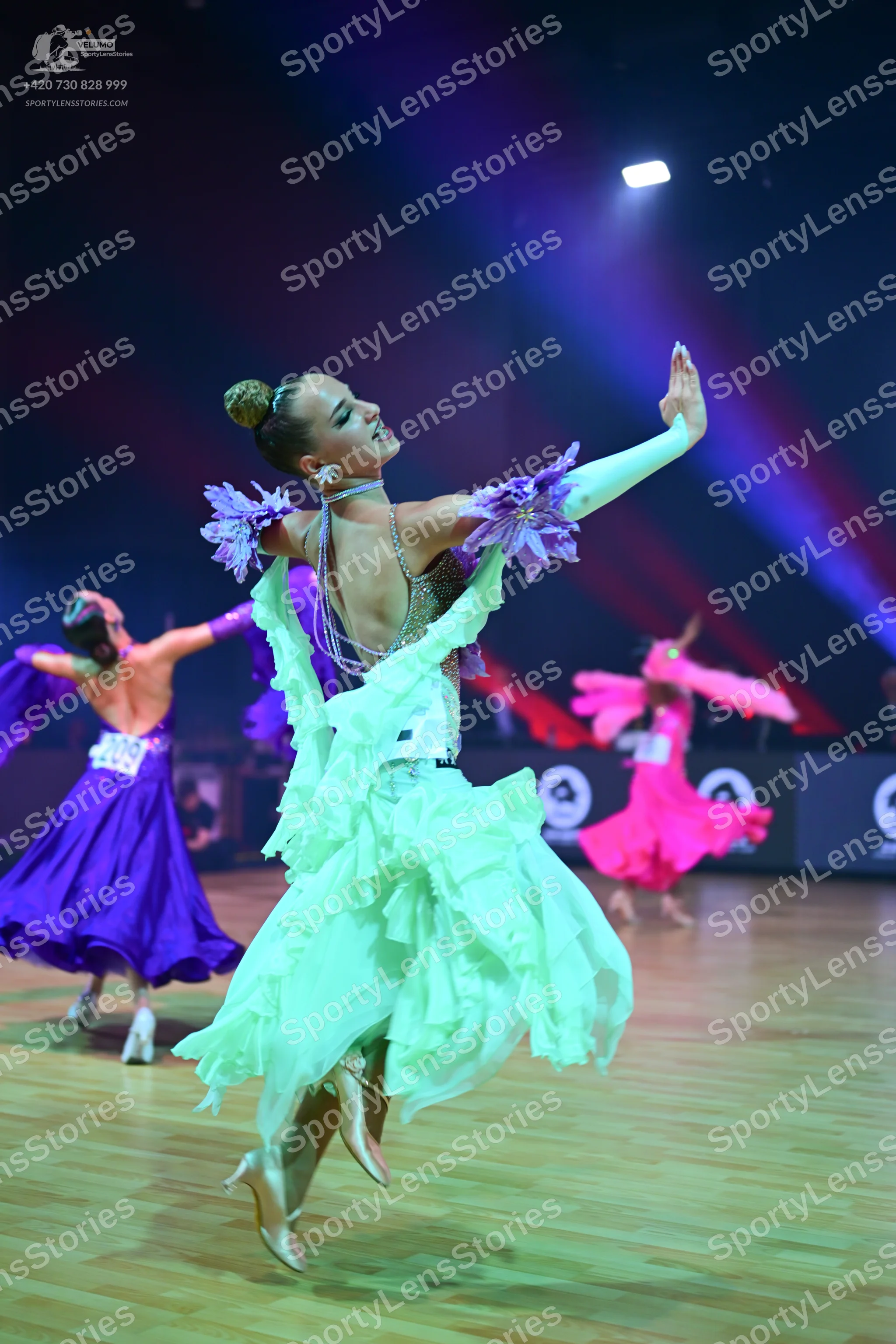 Dancesport competitor: Foreground dancer: mint green ballroom gown with voluminous ruffled layers of li