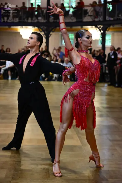 Dancesport competitor: Male dancer: black long-sleeved shirt with red sequined embellishments on the ch