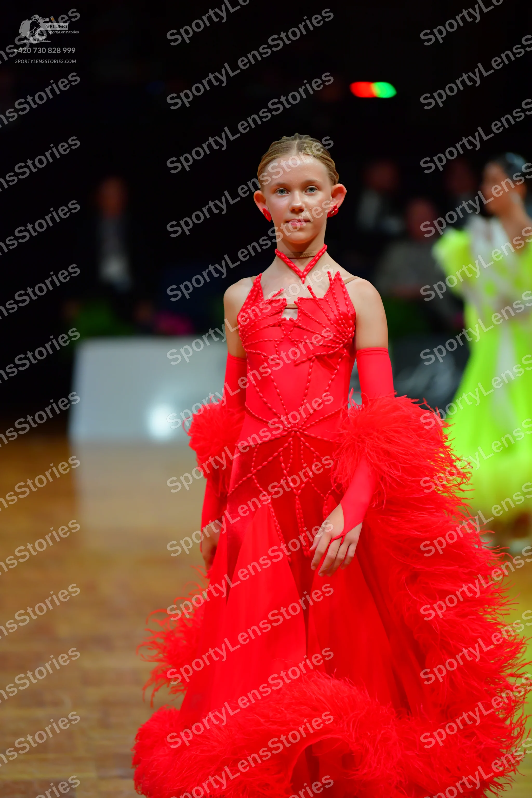 Dancesport competitor: Female dancer in foreground: red ballroom dress with a voluminous, textured, fea