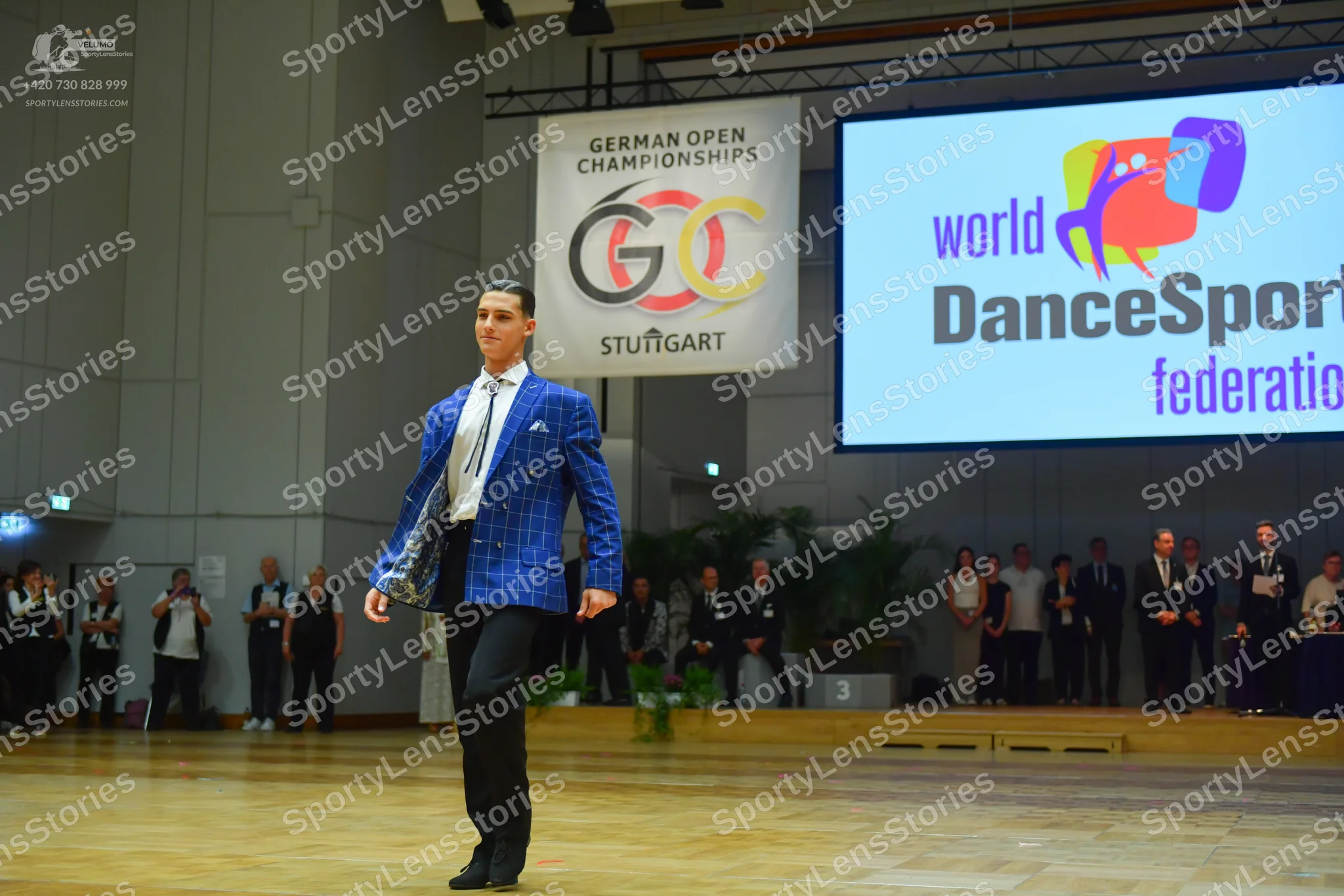 Dancesport competitor: Male dancer: bright blue patterned blazer, white shirt, blue and white patterned