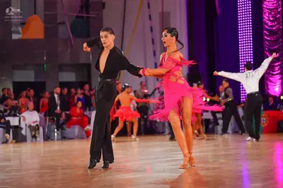 Dancesport competitor #27: Male dancer in foreground: black long-sleeved shirt with a deep neckline and bla