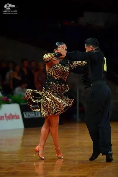 Dancesport competitor: Male dancer: black long-sleeved shirt with yellow/gold detail on the shoulder an