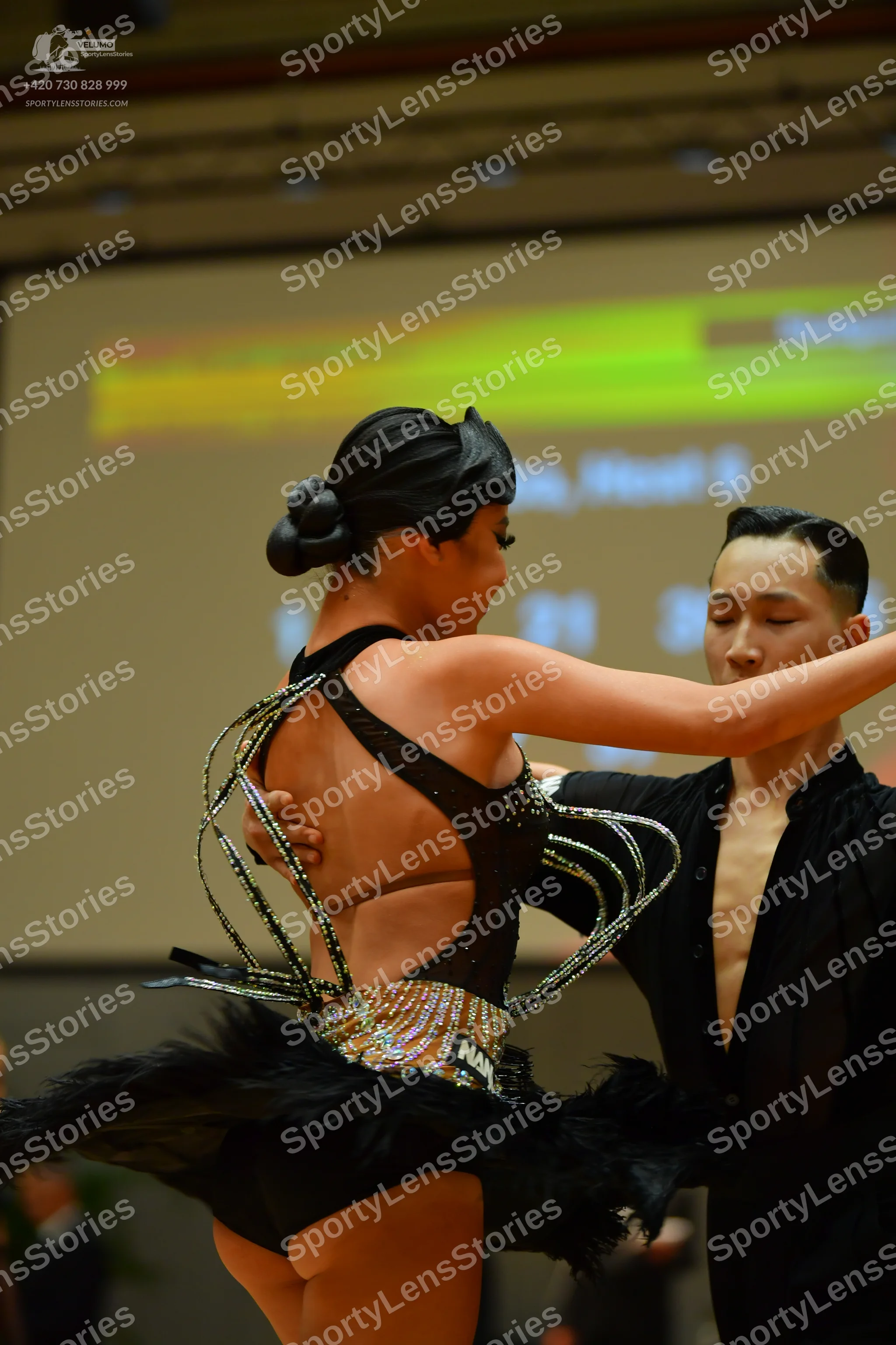 Dancesport competitor: Female dancer: black Latin dance costume featuring thin, decorative, crisscrossi