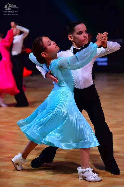 Dancesport competitor: Female dancer: light blue satin dress with long sleeves and a pleated skirt