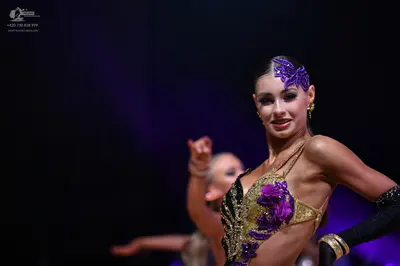 Dancesport competitor: Female dancer: gold and purple sequined Latin costume with a purple sequin hair 