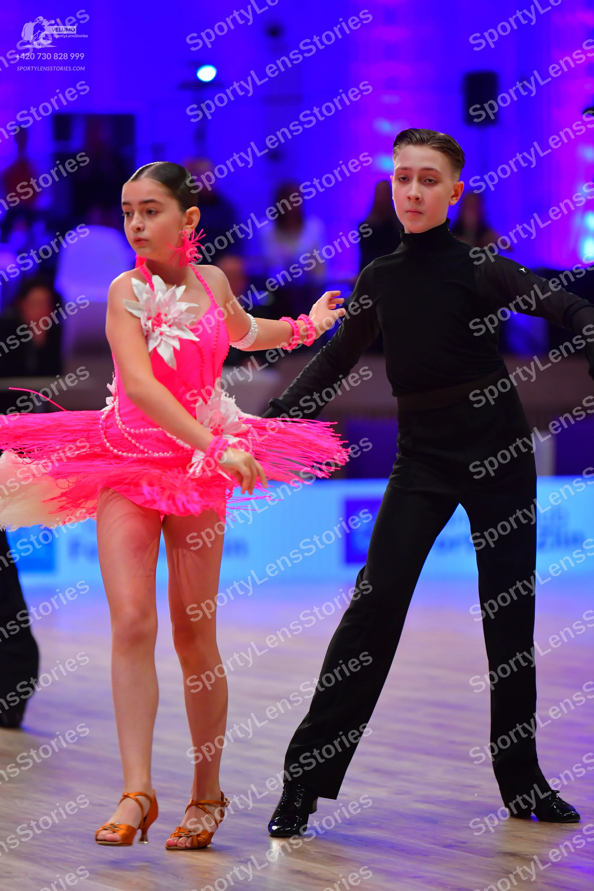 Dancesport competitor: Female dancer: bright pink Latin dance dress with white floral embellishments an