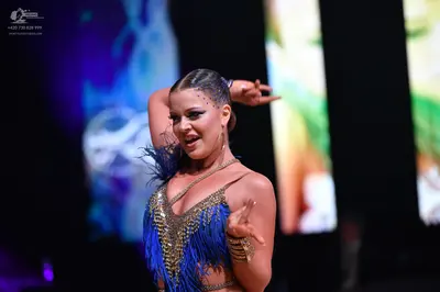 Dancesport competitor: Female dancer: blue Latin dance dress with blue fringe and gold/bronze sequins o