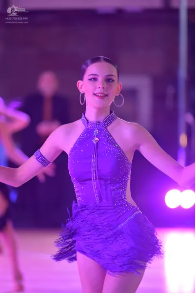 Dancesport competitor: Female dancer: purple latin dress with halter neck, rhinestone embellishments, a