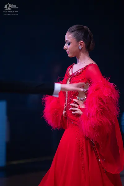 Dancesport competitor: Female dancer: red ballroom gown with feather-trimmed sleeves and crystal embell