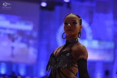Dancesport competitor: Female dancer: black latin dress with strappy details, sequins, and fringe