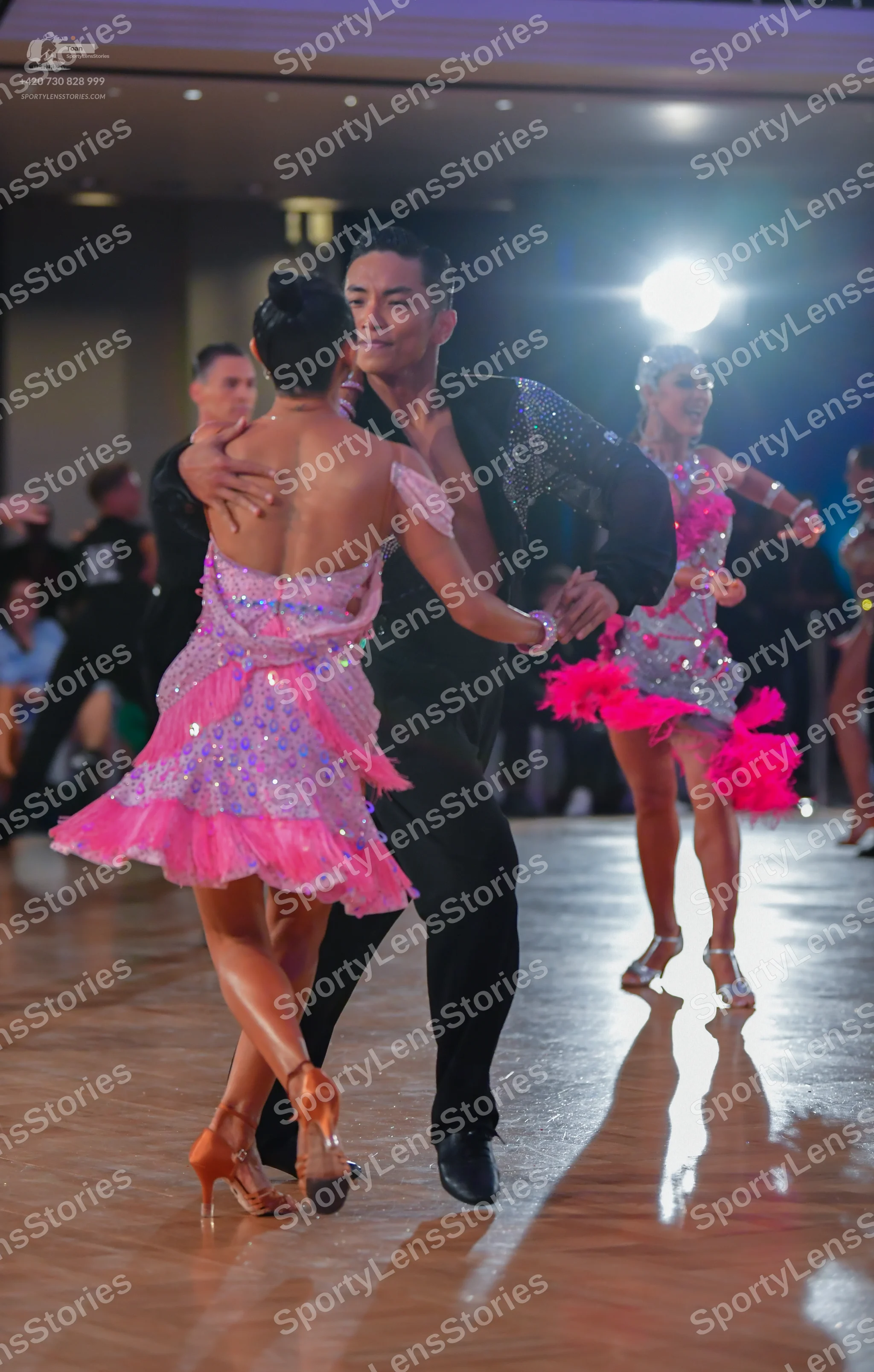 Dancesport competitor: Female dancer (foreground): pink and purple sequined Latin dress with ruffled la