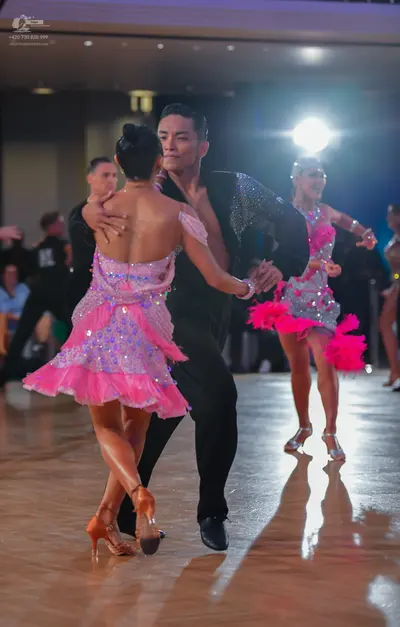 Dancesport competitor: Female dancer (foreground): pink and purple sequined Latin dress with ruffled la