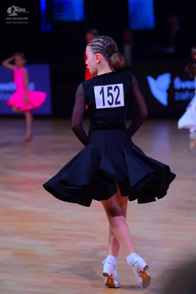 Dancesport competitor: Female dancer (center): black long-sleeved dress with a flared, ruffled skirt
