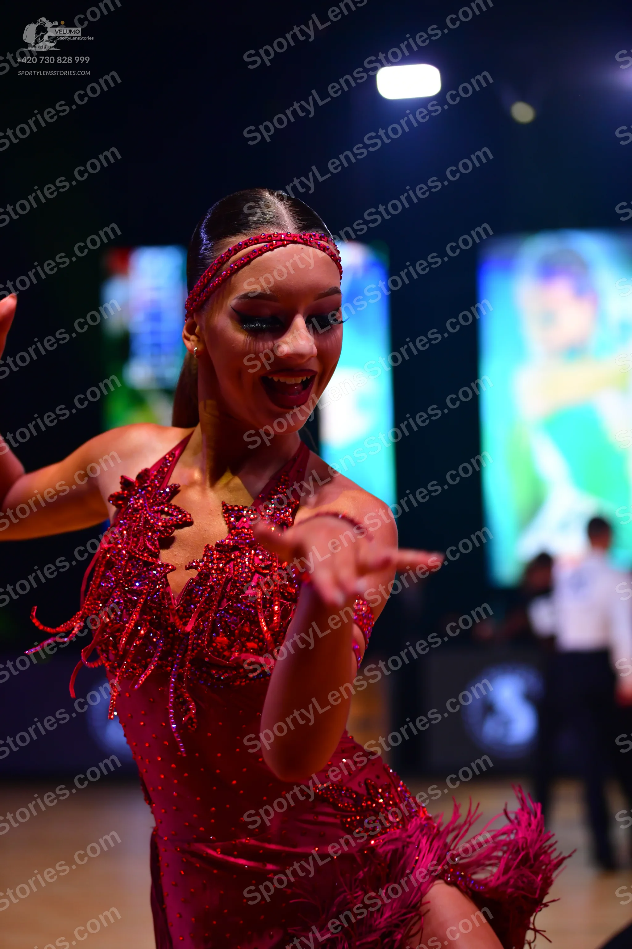 Dancesport competitor: Female dancer: dark red Latin dress with sequins and fringe-like details, and a 