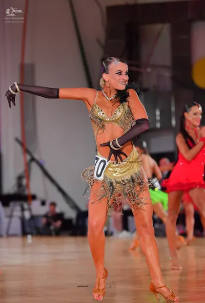 Dancesport competitor #70: Female dancer in foreground: gold sequin two-piece latin costume with fringe and