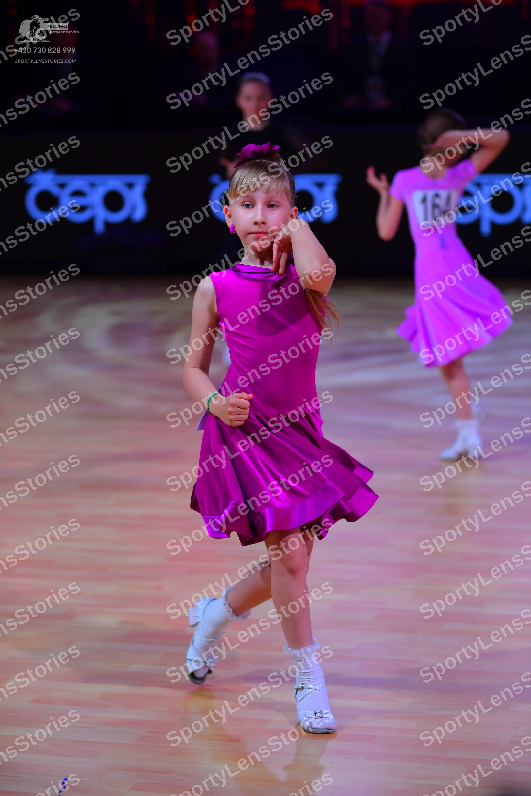 Dancesport competitor: Female dancer 1: bright pink satin sleeveless dress with a flared skirt, white d