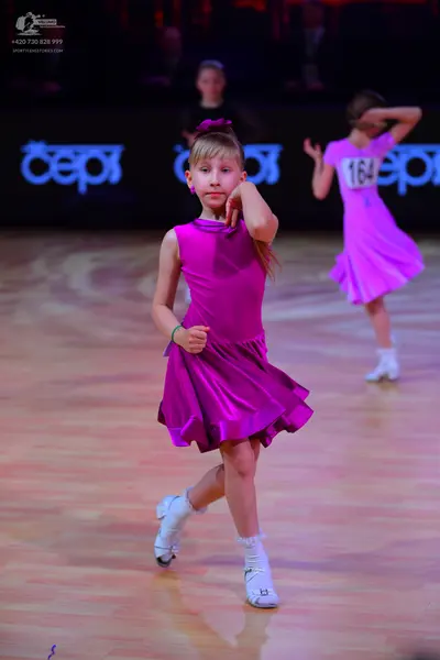 Dancesport competitor: Female dancer 1: bright pink satin sleeveless dress with a flared skirt, white d