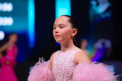 Dancesport competitor: Female dancer in foreground: light pink sleeveless dress with a white sequined f