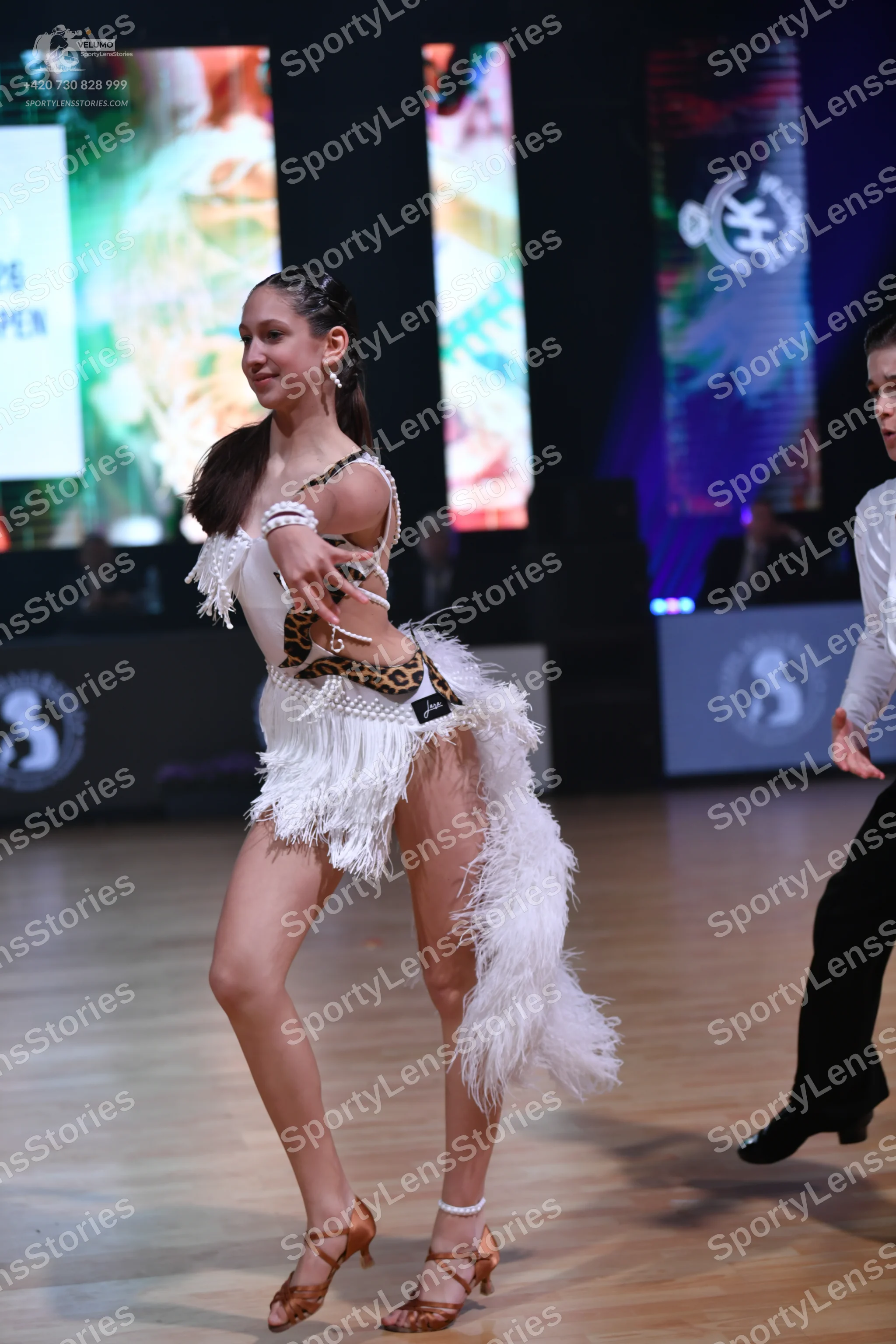 Dancesport competitor: Female dancer: white Latin dance costume with leopard print accents, featuring l