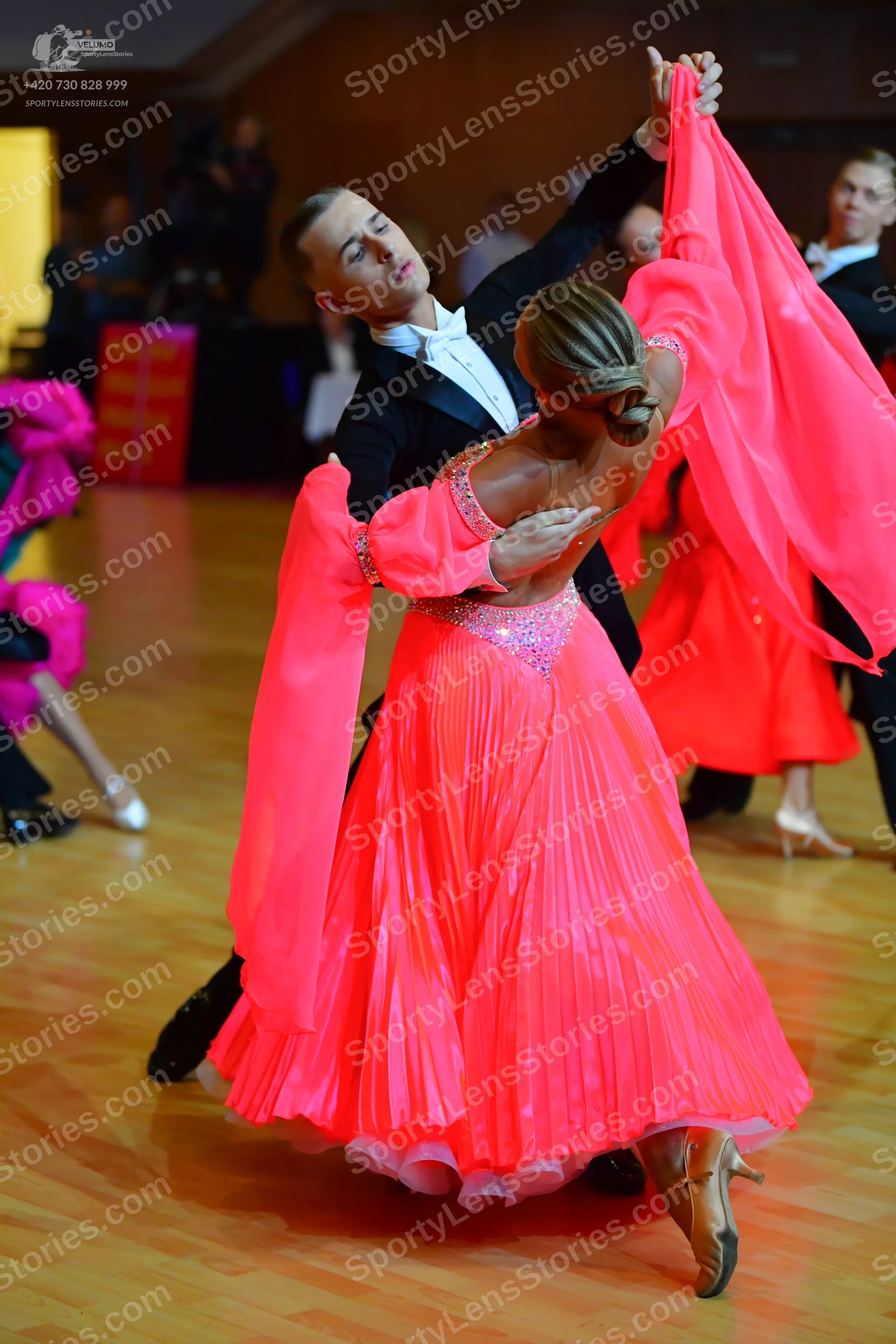Dancesport competitor: Main female dancer: bright pink ballroom dress with a sequin-embellished bodice,