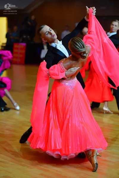 Dancesport competitor: Main female dancer: bright pink ballroom dress with a sequin-embellished bodice,