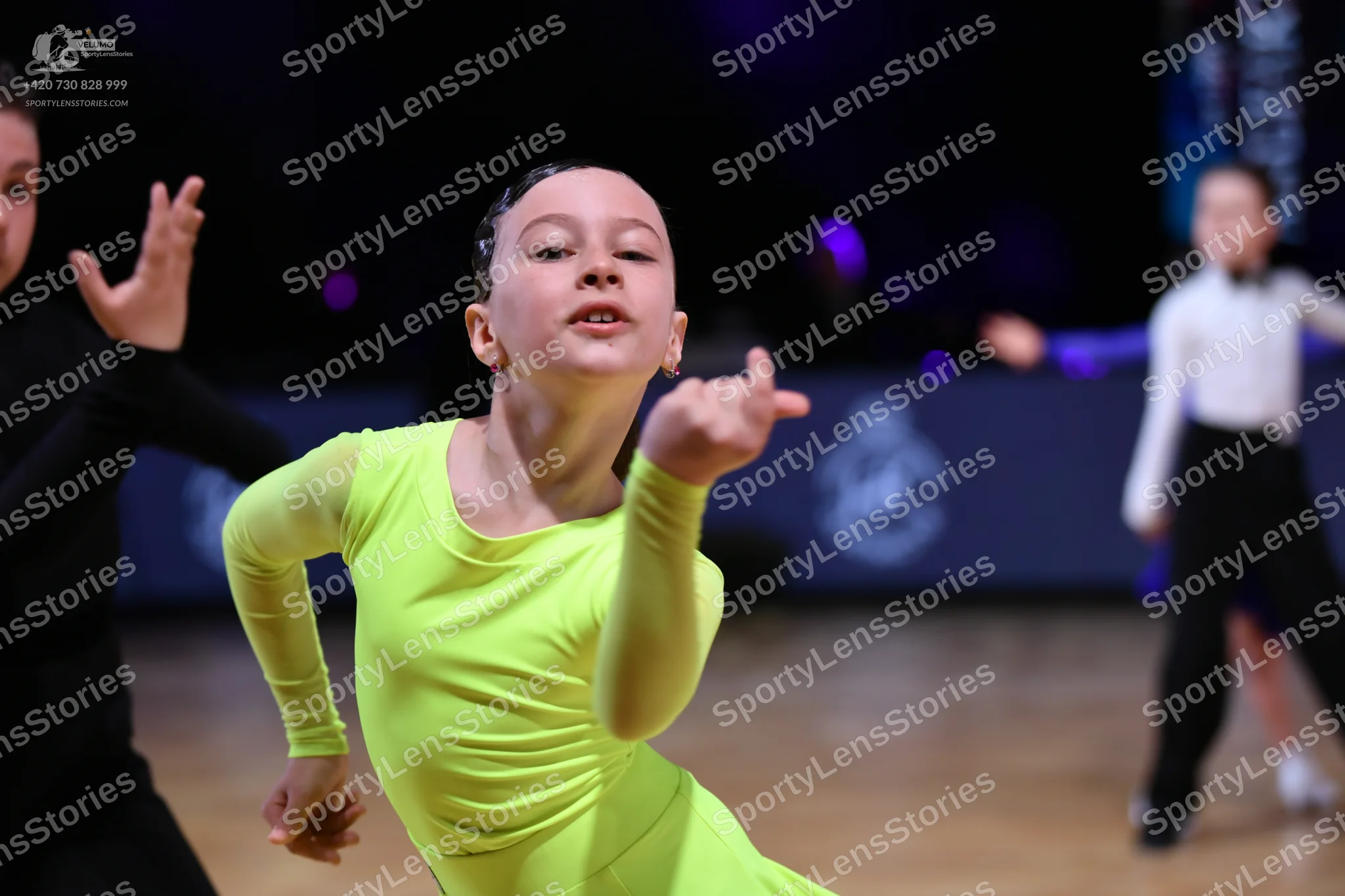 Dancesport competitor: Female dancer in foreground: lime green long-sleeved latin dress