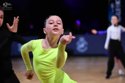 Dancesport competitor: Female dancer in foreground: lime green long-sleeved latin dress