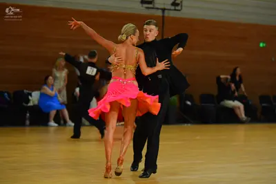 Dancesport competitor: Female dancer: pink latin dress with a sequined beige bodice and a ruffled skirt