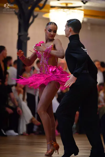 Dancesport competitor: Female dancer: pink latin dress with sequin embellishments and pink feather/frin