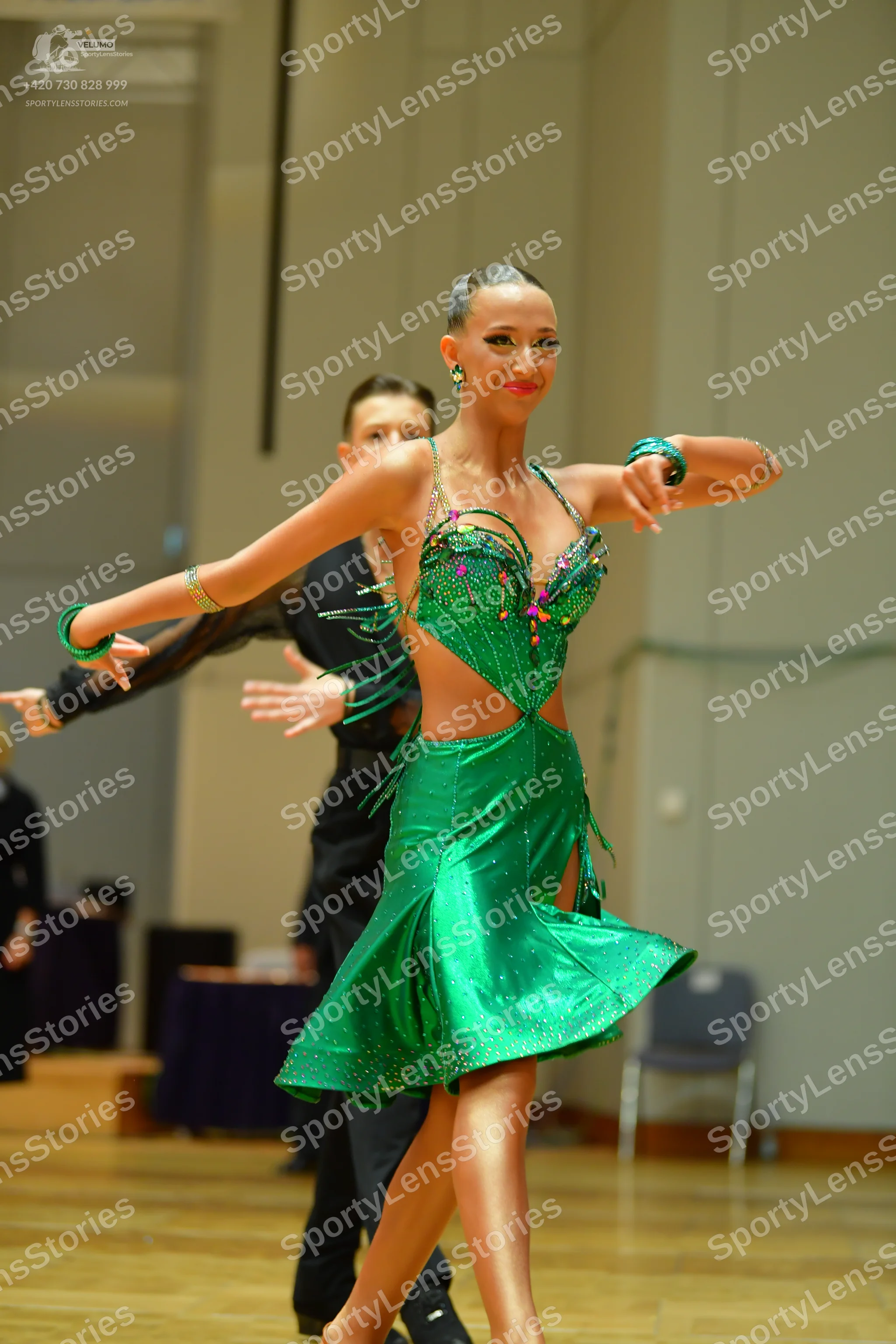 Dancesport competitor: Female dancer: emerald green satin latin dress with cutouts, fringe, and spaghet