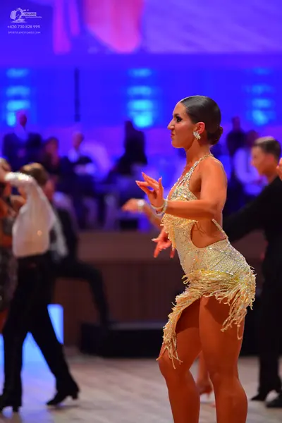 Dancesport competitor: Female dancer: light gold sequined Latin dress with fringe