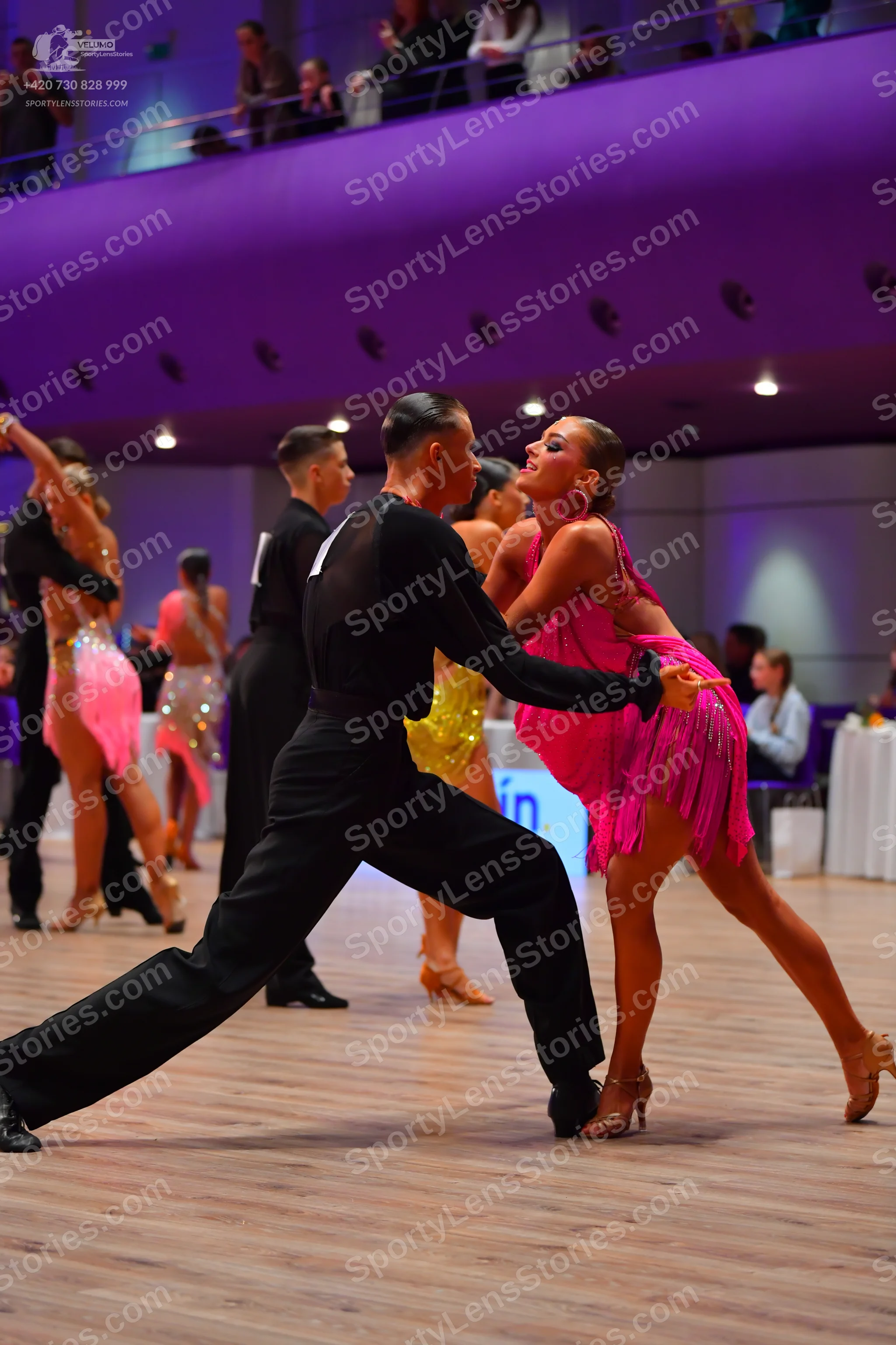 Dancesport competitor: Male dancer in foreground: black long-sleeve shirt and black trousers