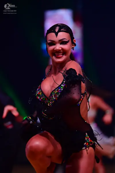 Dancesport competitor: Female dancer: black Latin dance costume featuring colorful sequins, sheer mesh 