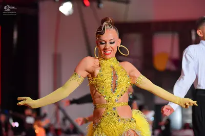 Dancesport competitor: Female dancer: yellow latin dress with sequins, fringe, and cutouts, matching lo