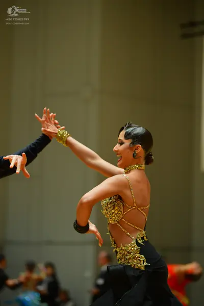 Dancesport competitor: Female dancer: gold latin dress with heavy sequin and stone embellishments, feat