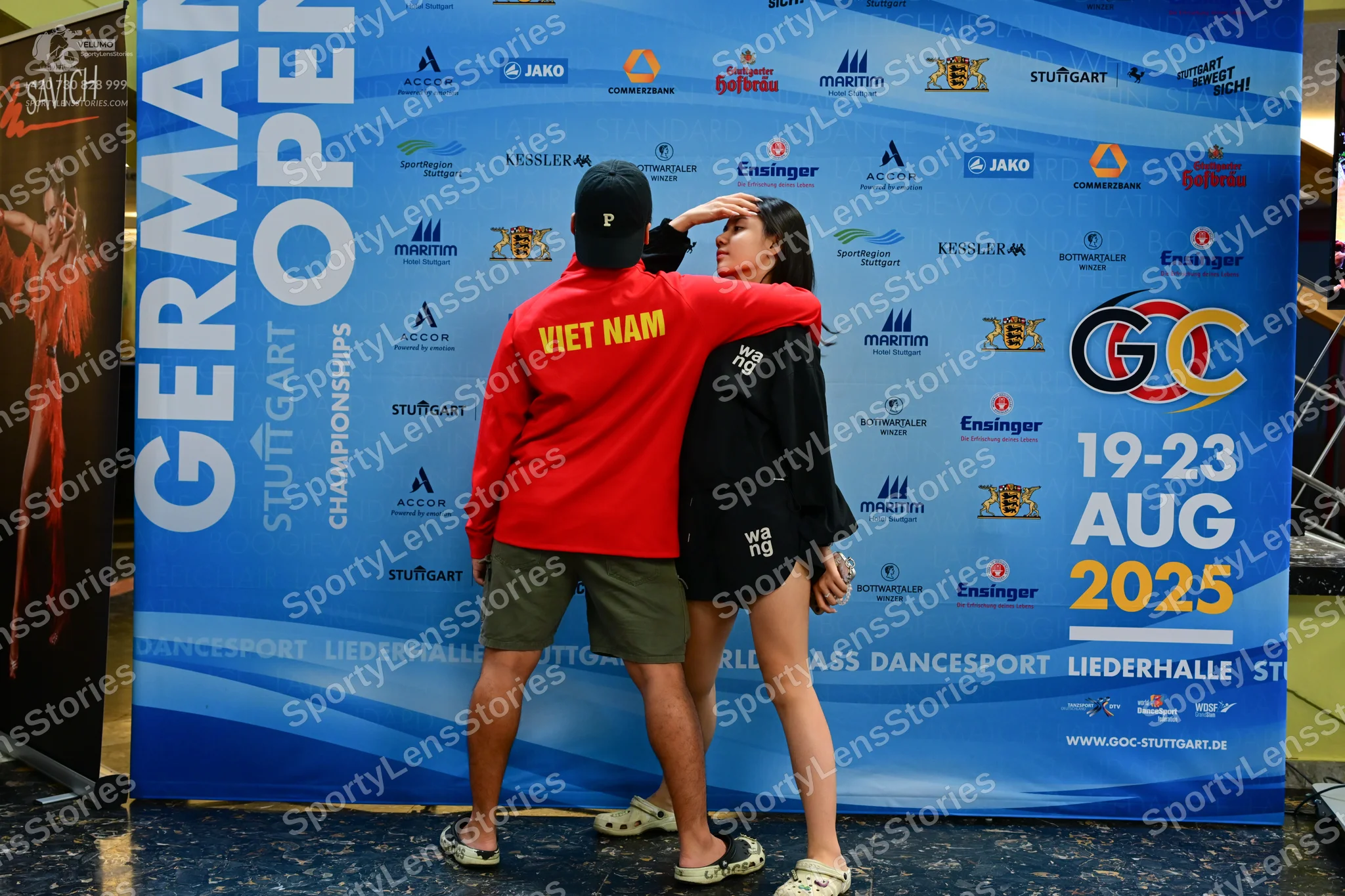 Dancesport competitor: Male dancer: red long-sleeved shirt with "VIET NAM" in yellow, dark cap, olive g