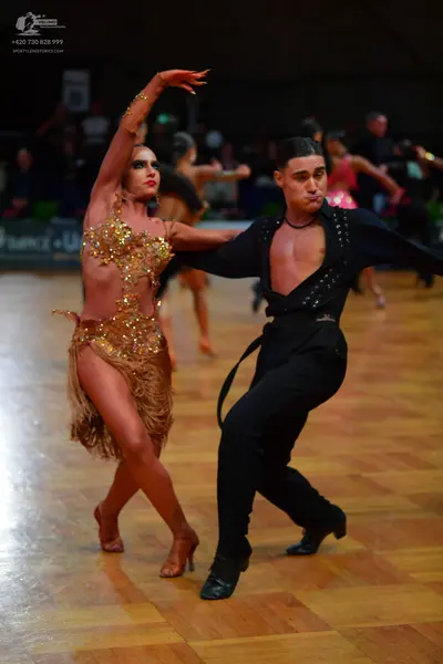Dancesport competitor: Female dancer: gold sequined latin dress with fringe and matching armbands
