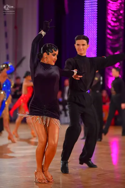 Dancesport competitor: Female dancer: black long-sleeved latin dress with silver fringe hem, silver wri