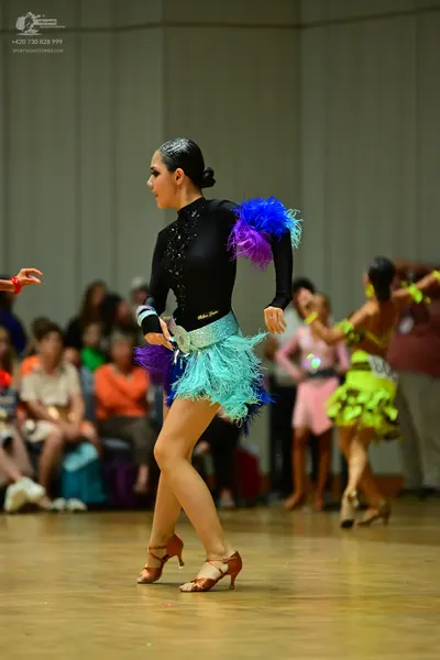 Dancesport competitor #86: Female dancer in foreground: black long-sleeved Latin dance dress with a high ne