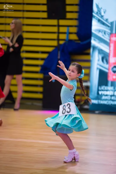 Dancesport competitor #83: Child** 
*   **Color:** Light Blue 
*   **Fabric:** Ruffled skirt fabric (likely