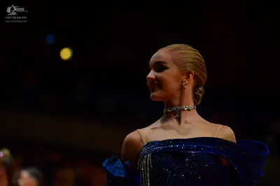 Dancesport competitor: Female dancer: dark blue off-the-shoulder ballgown covered in sequins, featuring