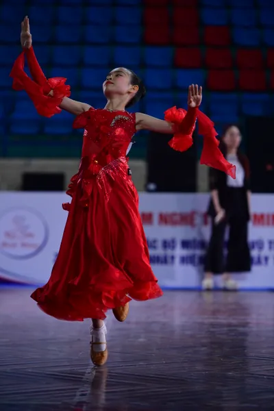 Dancesport competitor: Female:** Red Latin dress with a sweetheart neckline, a ruffled, flowing skirt w